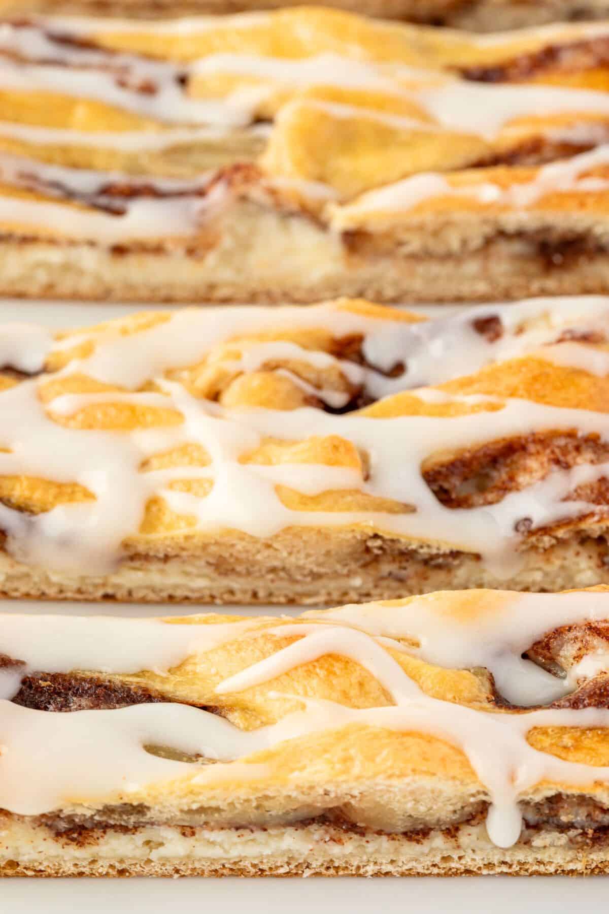 Slices of danish pastry with cinnamon and cream cheese filling and white icing drizzled on top.