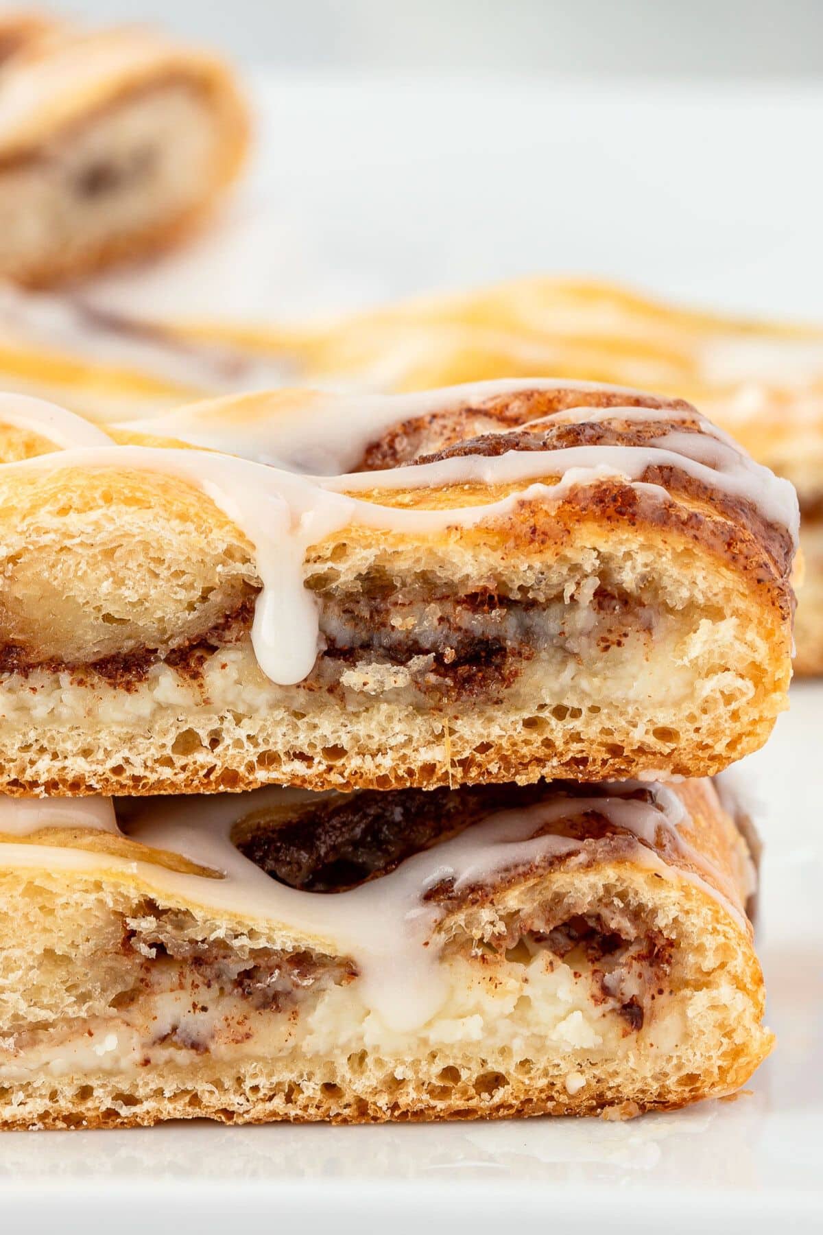 Two slices of the breakfast pastry showcasing the gooey filling with icing dripping down the side.