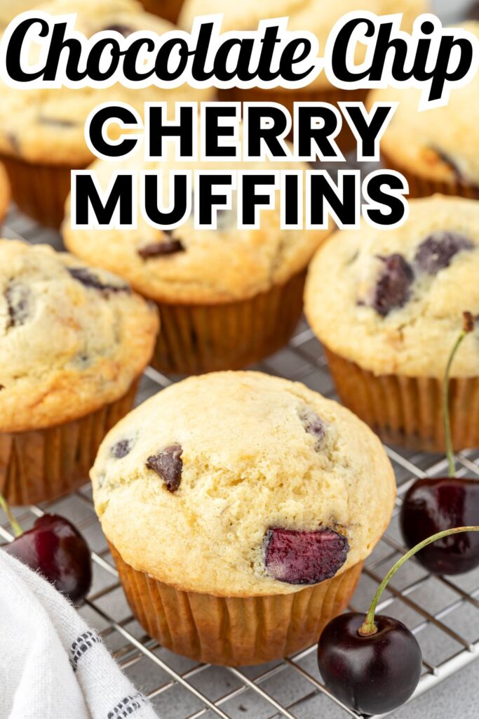 Muffins with chocolate chips and cherries studded throughout on a wire rack with some whole cherries surrounding.