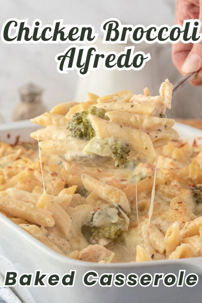 A spoon lifts cheesy chicken broccoli Alfredo casserole from a baking dish with penne pasta.