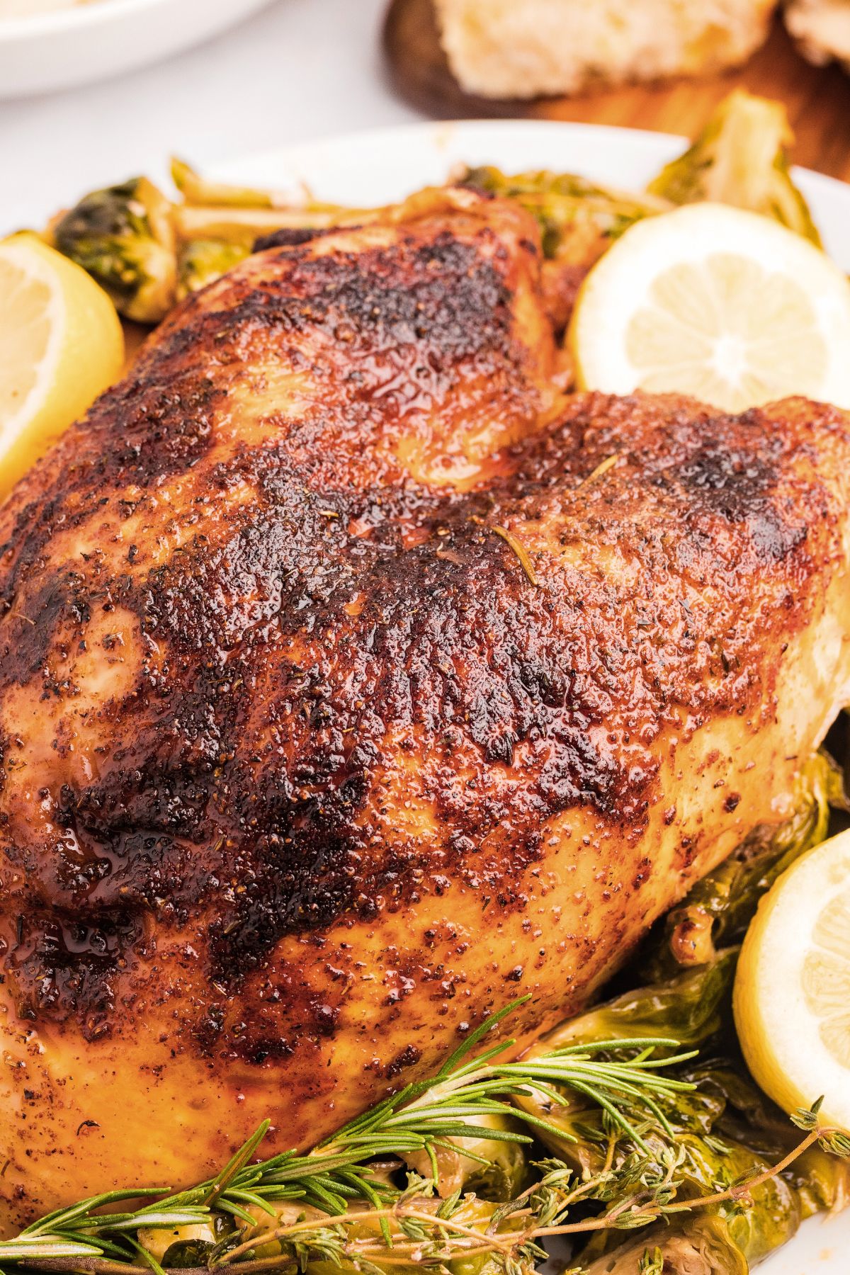 Roasted chicken breast with crispy skin, garnished with lemon slices and fresh rosemary.