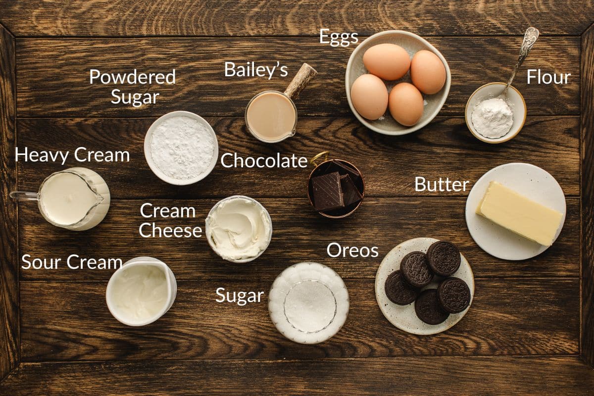 Various baking ingredients, including eggs, butter, Oreos, chocolate, and creams, labeled on a wooden table.