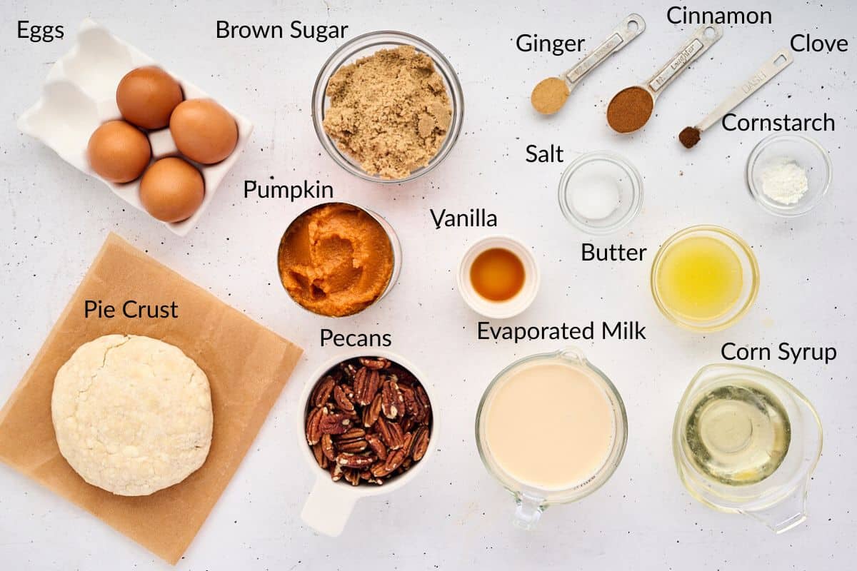 Top-down view of labeled ingredients for a pumpkin pecan pie, including eggs, pie crust, sugar, spices, and milk.