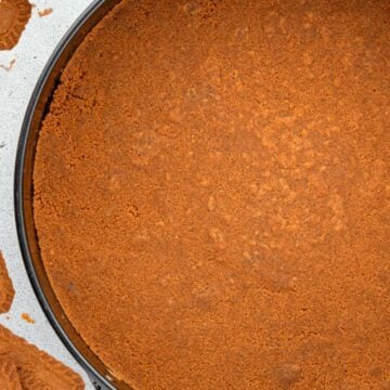 A round pan filled with a smooth, crumbly, brown biscuit crust on a light surface.