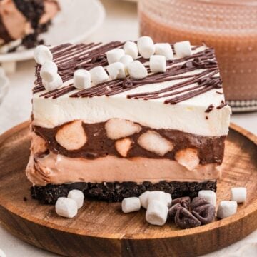A chocolate mousse dessert slice topped with whipped cream, mini marshmallows, and a chocolate drizzle.