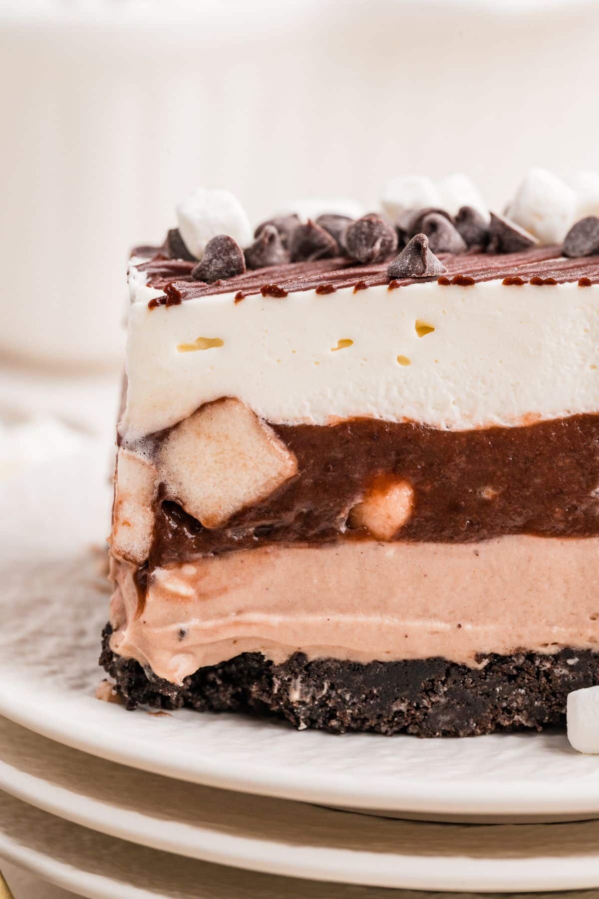 A close-up of a layered chocolate dessert lasagna topped with whipped cream, chocolate chips, and mini marshmallows.