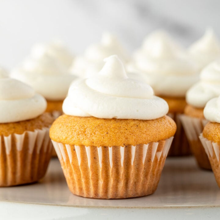Vanilla cupcakes with swirls of white frosting arranged on a plate.