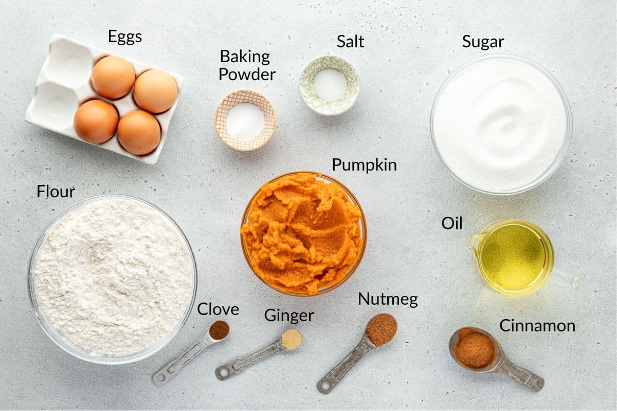 Top view of labeled baking ingredients: eggs, flour, sugar, pumpkin, oil, spices, baking powder, and salt.