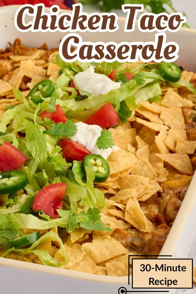 Chicken taco casserole topped with lettuce, tomato, jalapeños, sour cream, and crushed tortilla chips.