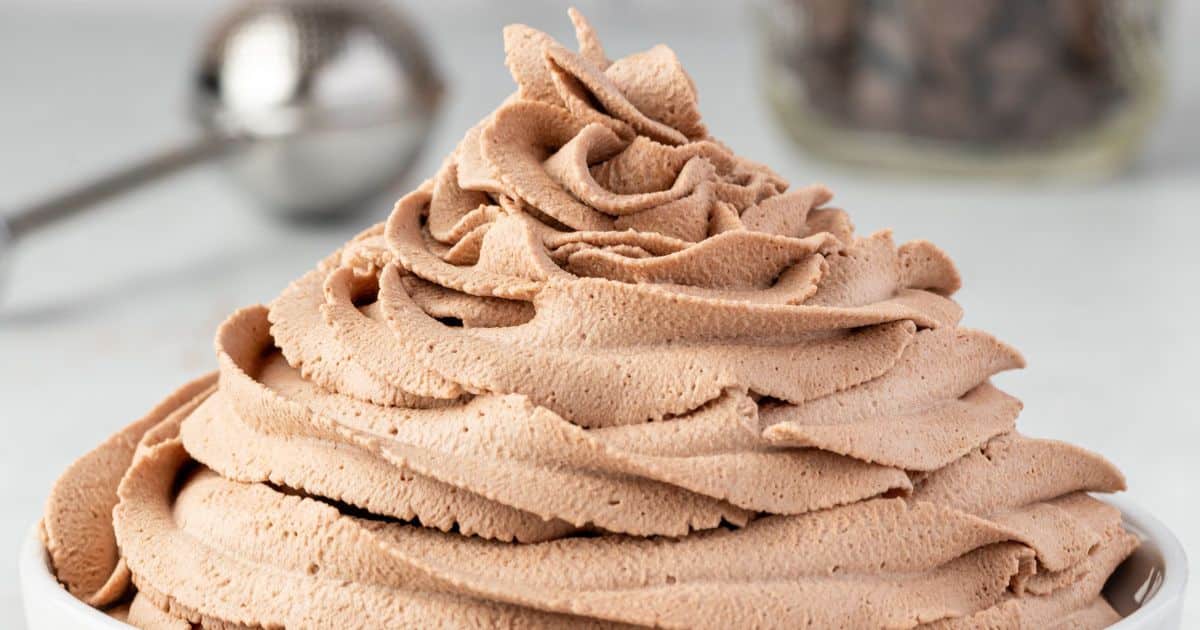 Chocolate whipped cream swirled in a bowl, with a blurred ice cream scoop in the background.
