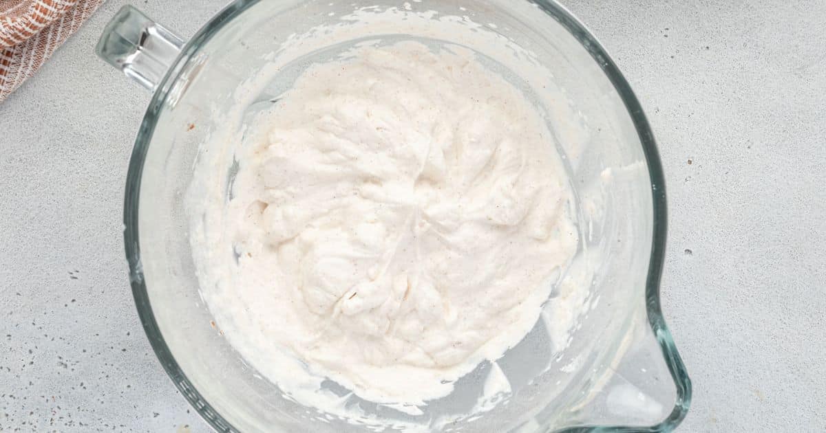 Thick white batter in a clear glass mixing bowl on a light gray countertop.
