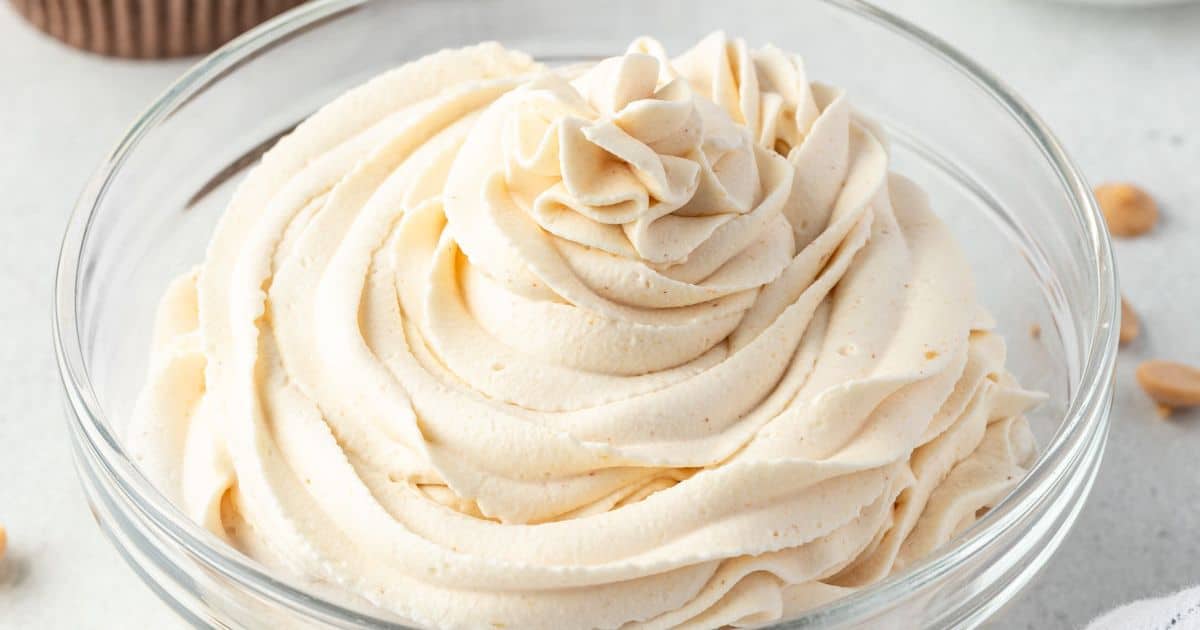 A glass bowl filled with swirled, creamy peanut butter frosting.
