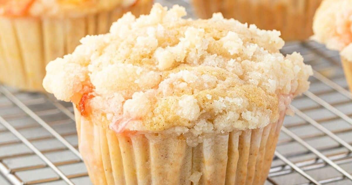 A close-up of a crumb-topped muffin cooling on a wire rack.