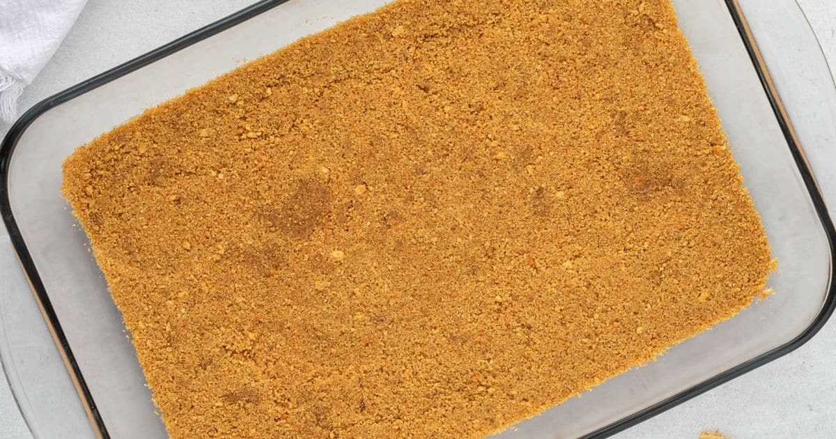 Rectangular glass dish filled with an even layer of crushed graham cracker crust.