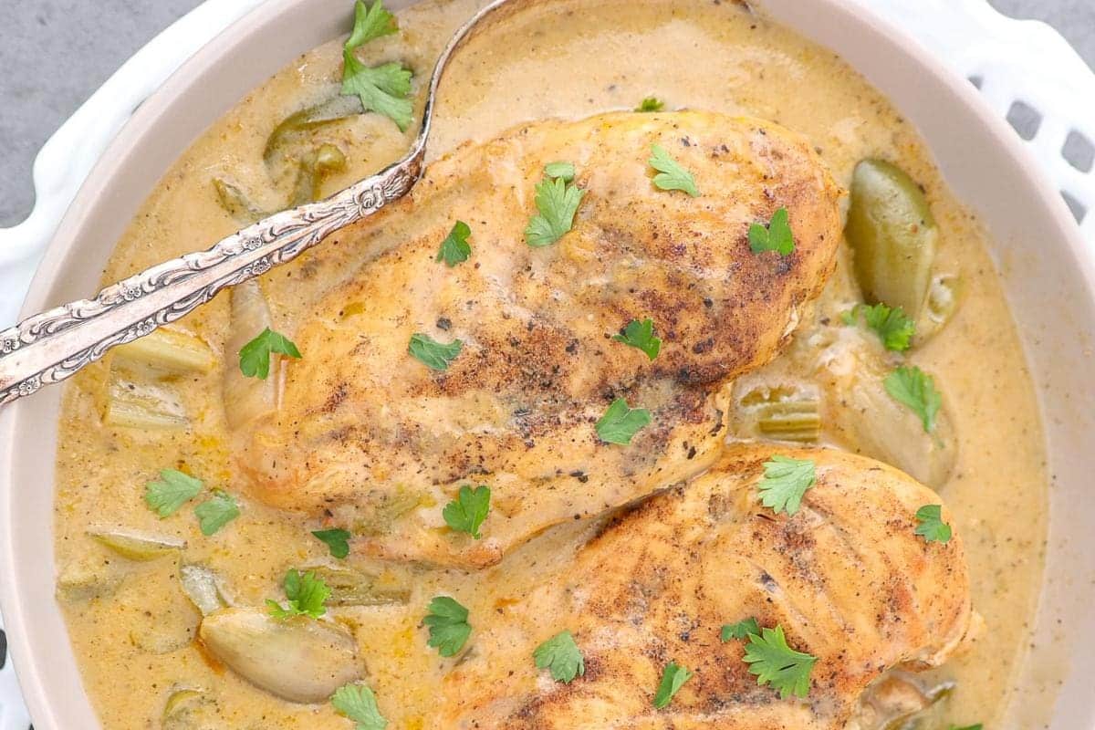 A bowl of chunky stew with meat and herbs, served next to crispy tortilla chips.