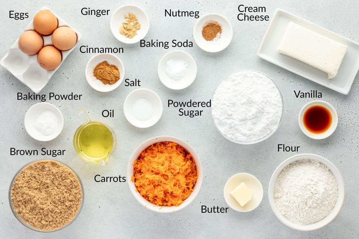 Bowls of carrot cake ingredients including eggs, flour, oil, sugar, spices, carrots, cream cheese, and butter.