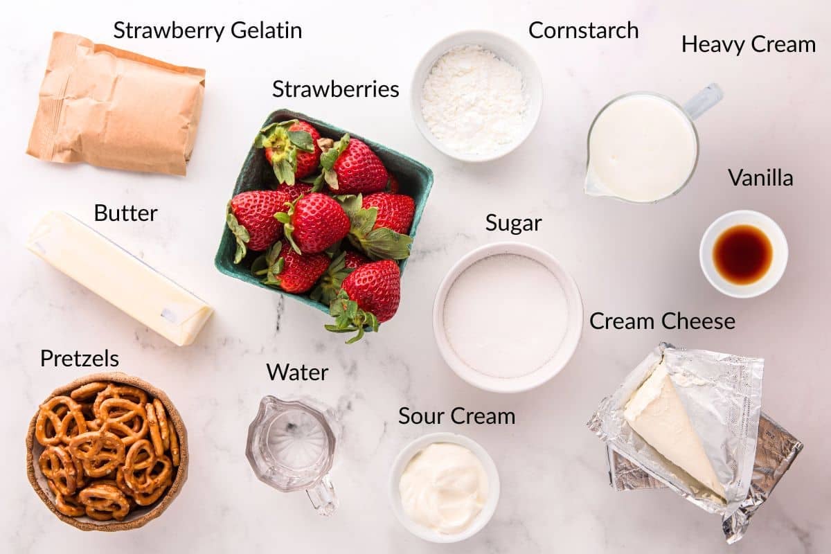 Ingredients for a strawberry dessert, labeled: gelatin, berries, cornstarch, cream, vanilla, sugar, cheese, butter, pretzels, water, sour cream.