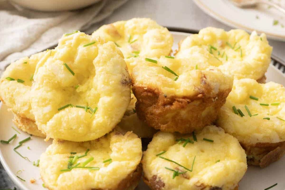 Mini egg muffins topped with chopped chives, arranged on a plate.