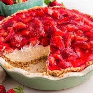 A strawberry cream pie with a slice missing, showing a creamy filling and fresh strawberry topping.