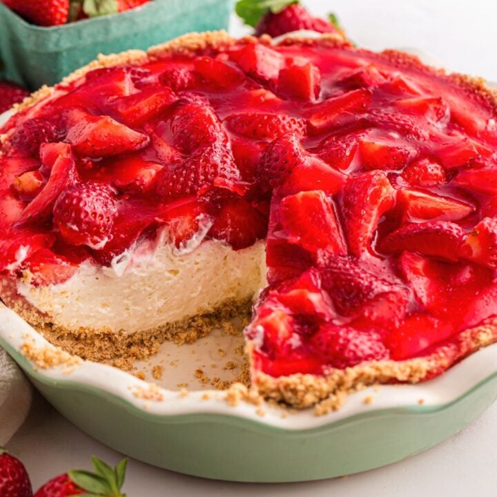 A strawberry cream pie with a slice missing, showing a creamy filling and fresh strawberry topping.
