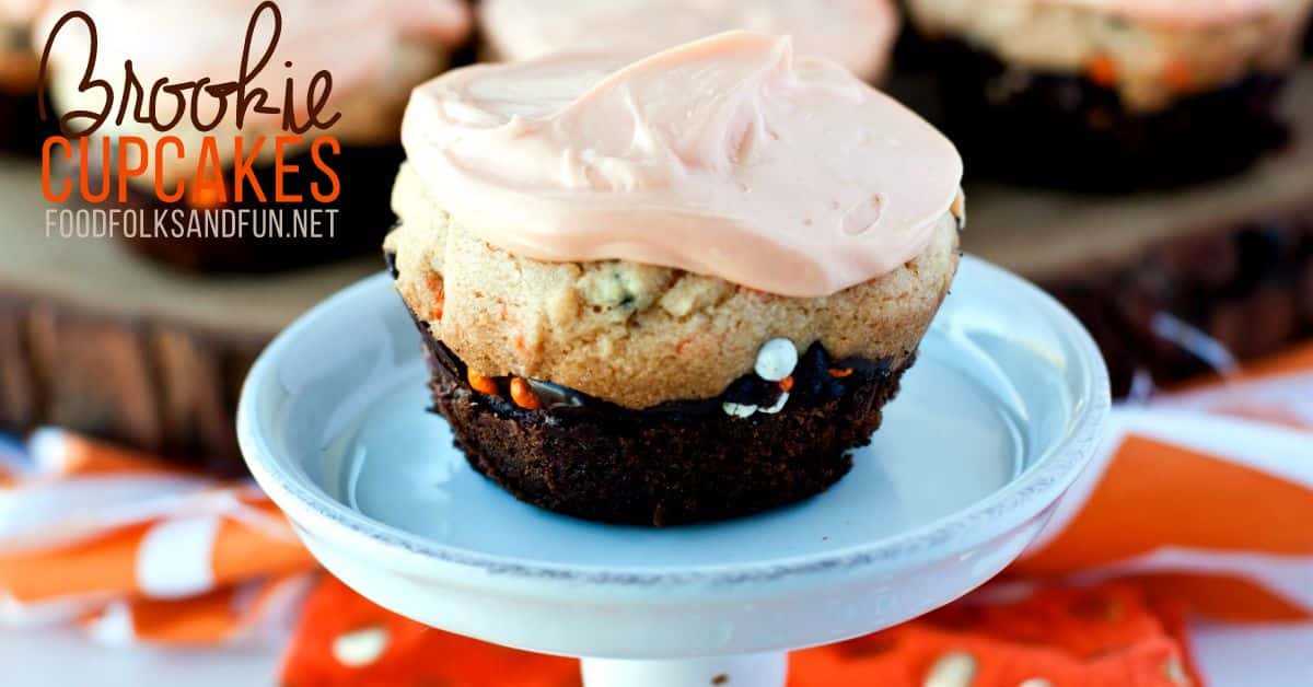 A brookie cupcake with pink frosting sits on a small cake stand, with orange and white decor.