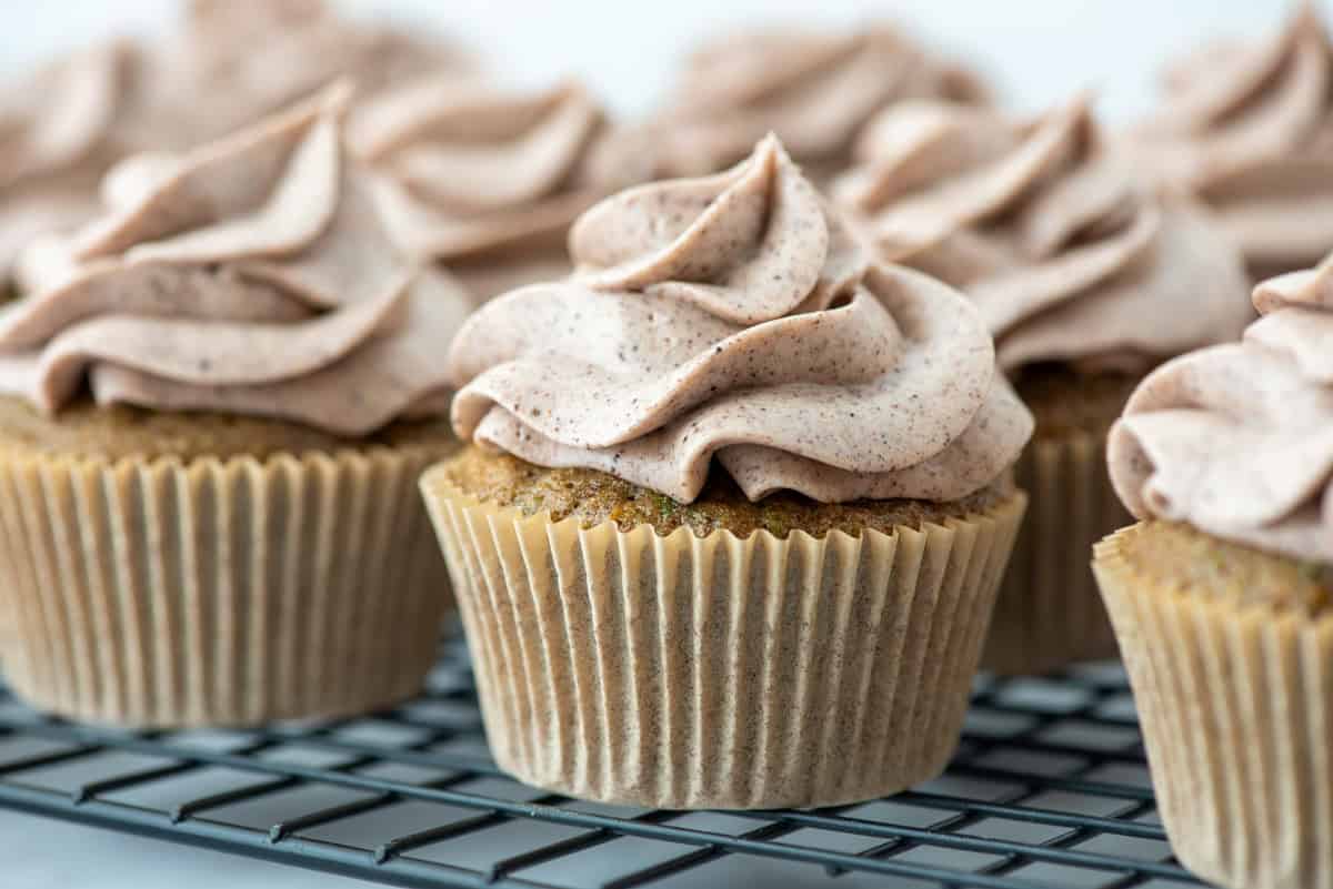Cupcakes with swirled cinnamon frosting sit on a cooling rack, ready to be served.