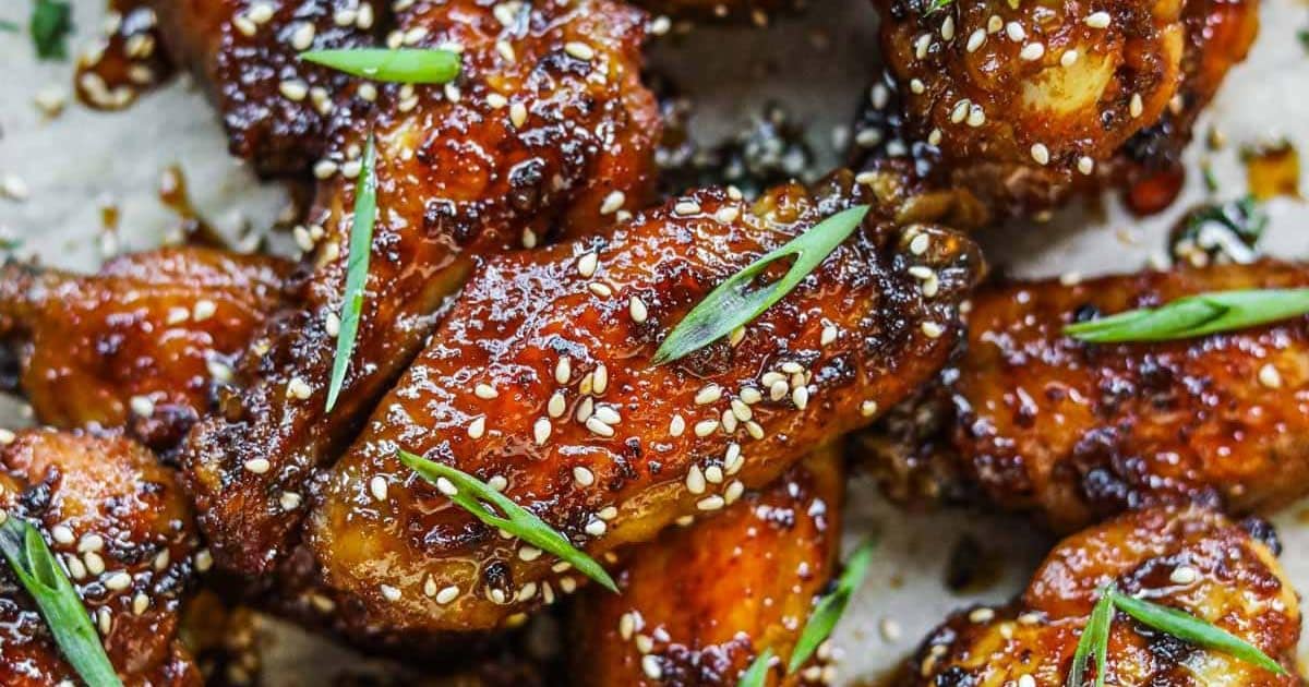 Crispy glazed chicken wings topped with sesame seeds and sliced green onions.