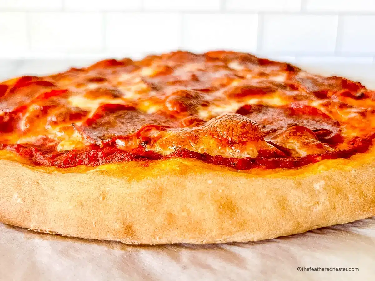 Close-up of a thick-crust pepperoni pizza with melted cheese, on a white surface.