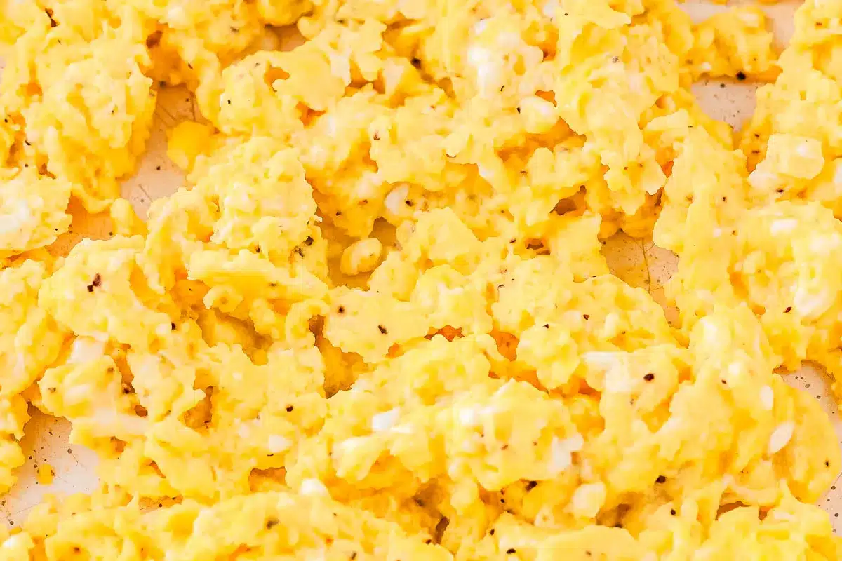 Close-up of scrambled eggs with visible black pepper on a light surface.