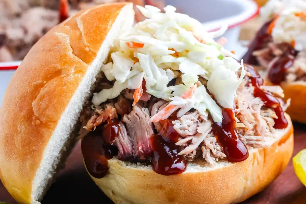 Pulled pork sandwich topped with barbecue sauce and coleslaw on a soft bun.