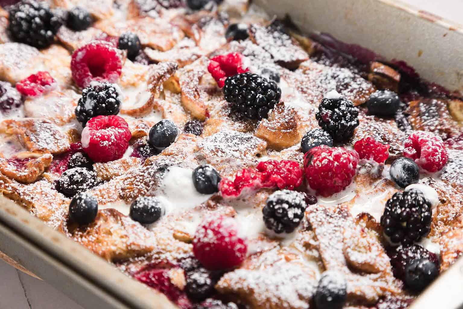 Baked French toast topped with fresh raspberries, blackberries, blueberries, and powdered sugar.