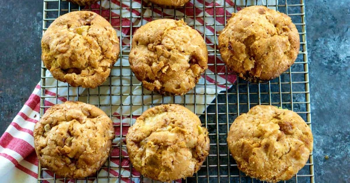 Nine golden brown muffins cooling on a wire rack over a red and white striped kitchen towel.