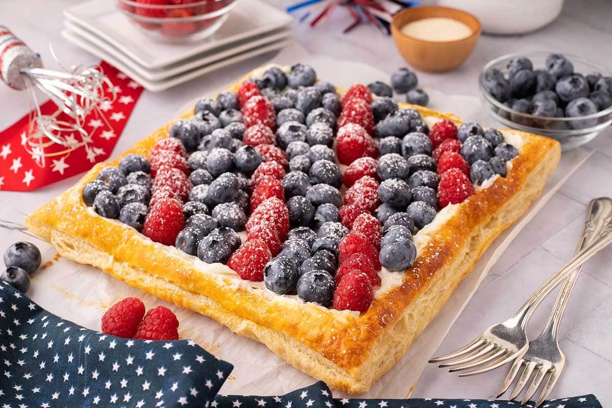 A pastry decorated with blueberries and raspberries in a flag pattern, dusted with powdered sugar.