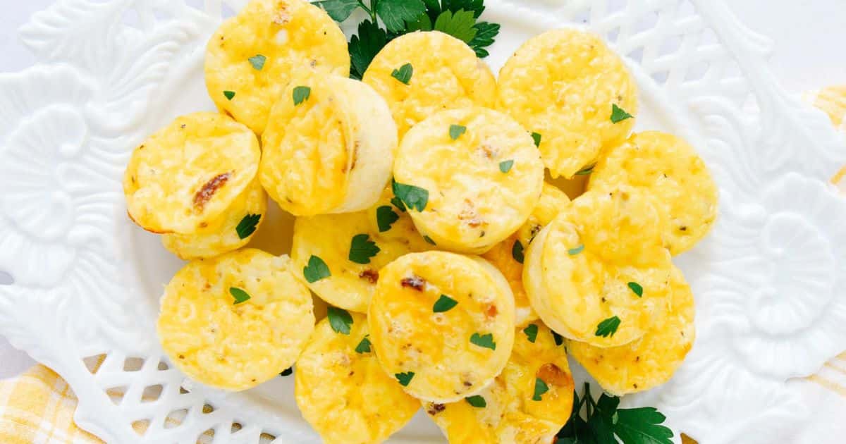 Mini egg bites garnished with chopped parsley on a white decorative plate.