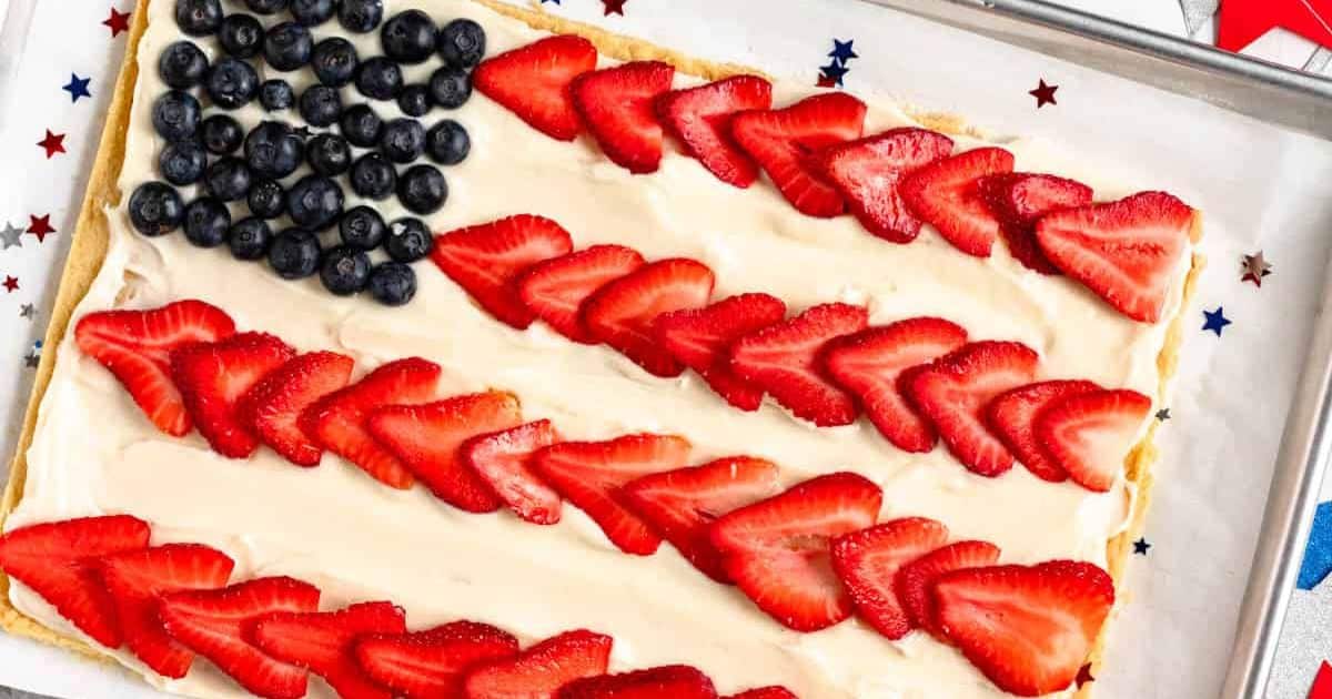 Rectangular dessert decorated like the U.S. flag with blueberries and strawberry slices on creamy frosting.