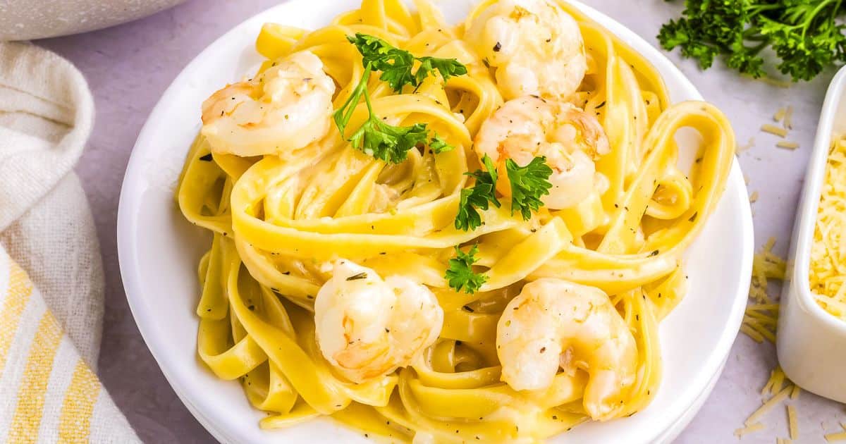A plate of fettuccine pasta with shrimp in creamy sauce, garnished with fresh parsley.
