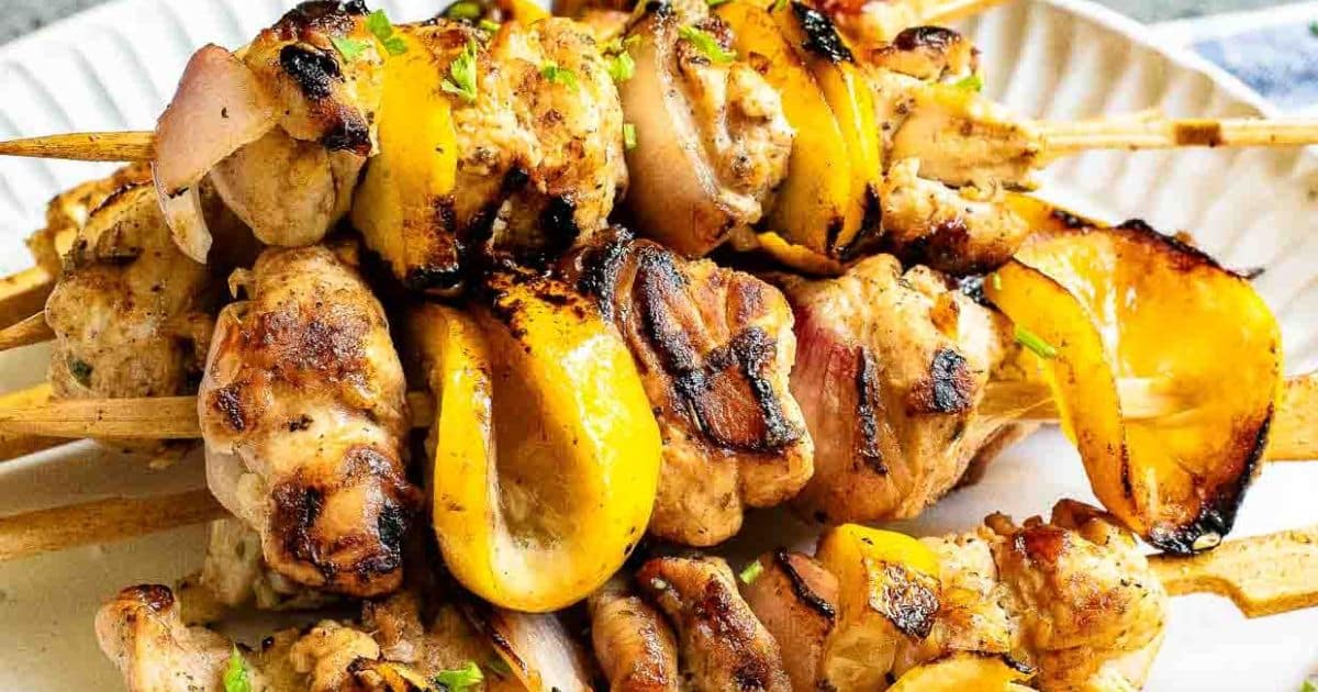 Grilled chicken and yellow bell pepper skewers served on a white plate.