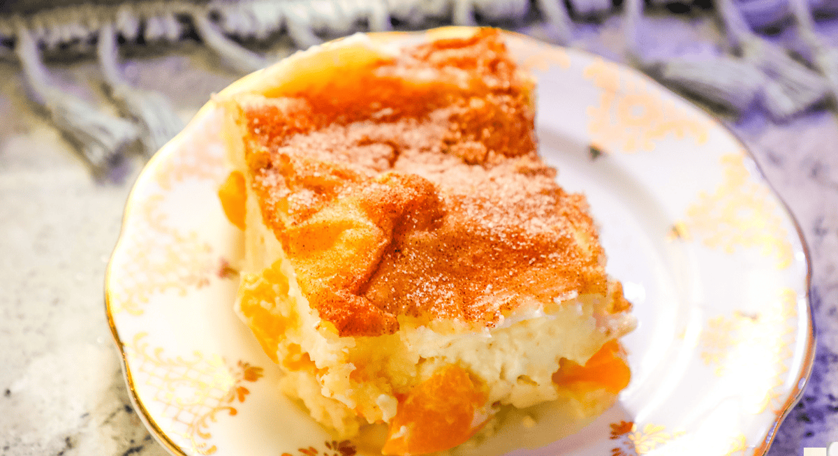 A slice of fruit-filled cake with a golden crust on a decorative plate.