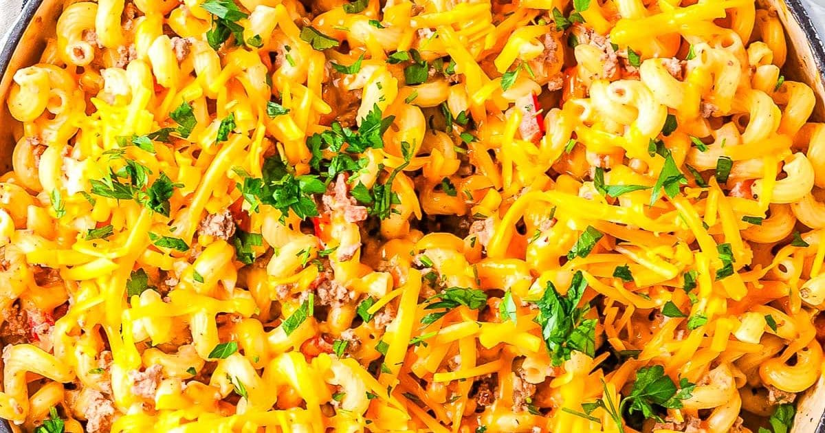Macaroni pasta with ground beef, melted cheddar cheese, and parsley garnished on top.