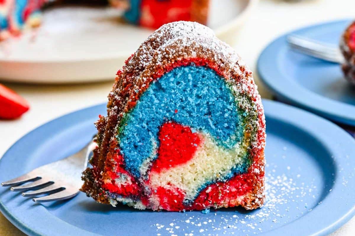 A slice of vibrant red, blue, and white marble Bundt cake on a blue plate with a fork.