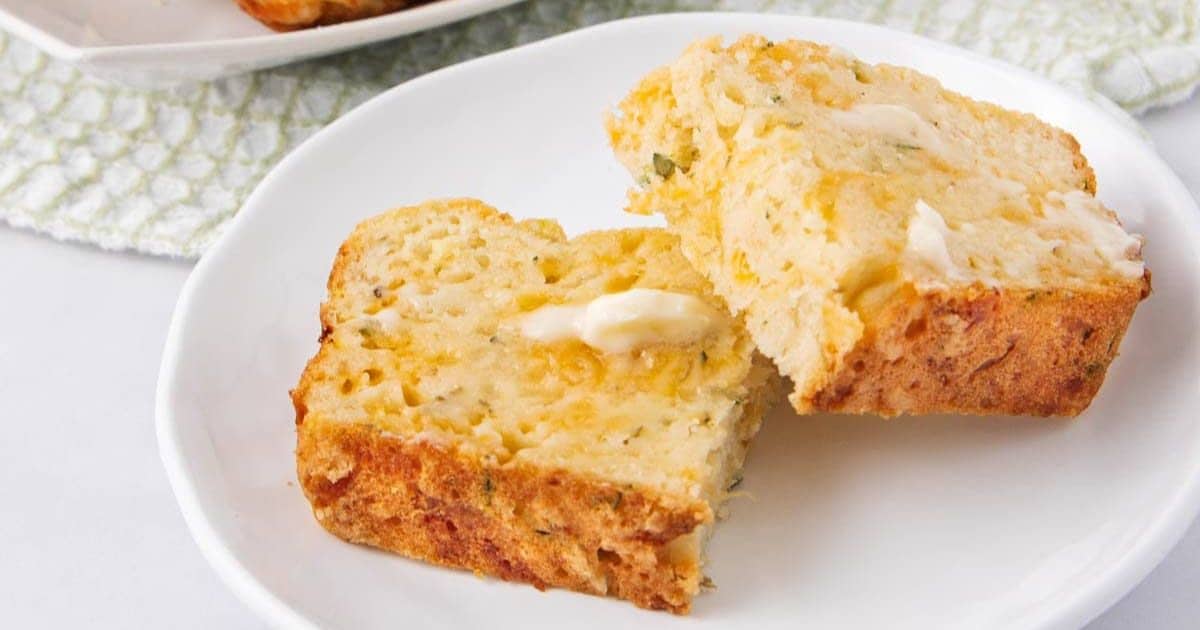 Two slices of cheesy bread with melted butter on a white plate.
