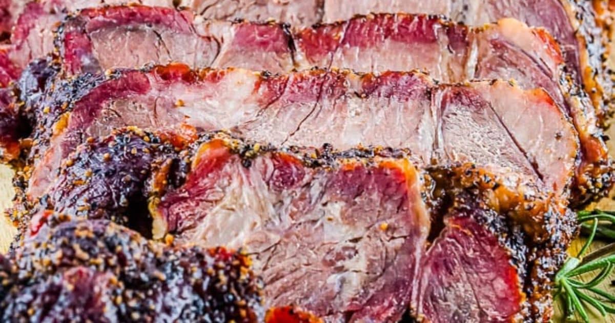 Sliced, juicy, seasoned beef roast with a peppery crust, shown close up.