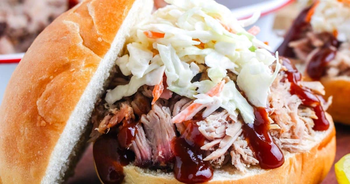 Pulled pork sandwich topped with barbecue sauce and coleslaw in a soft bun.
