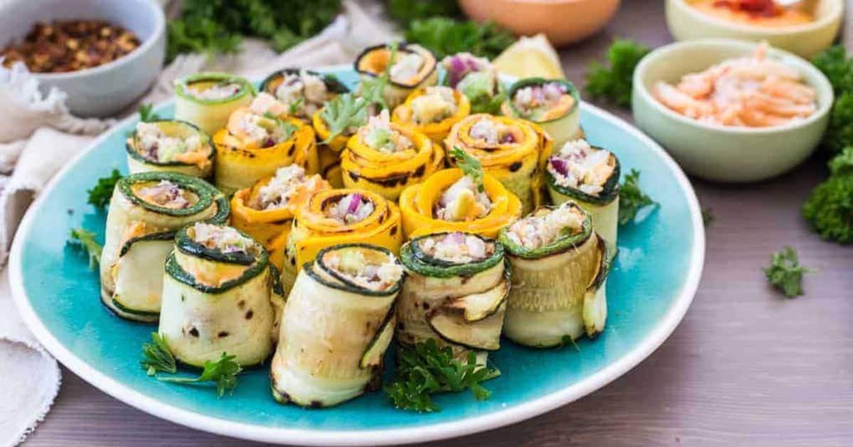 Plate of zucchini and yellow squash roll-ups filled with a creamy mixture, garnished with parsley.