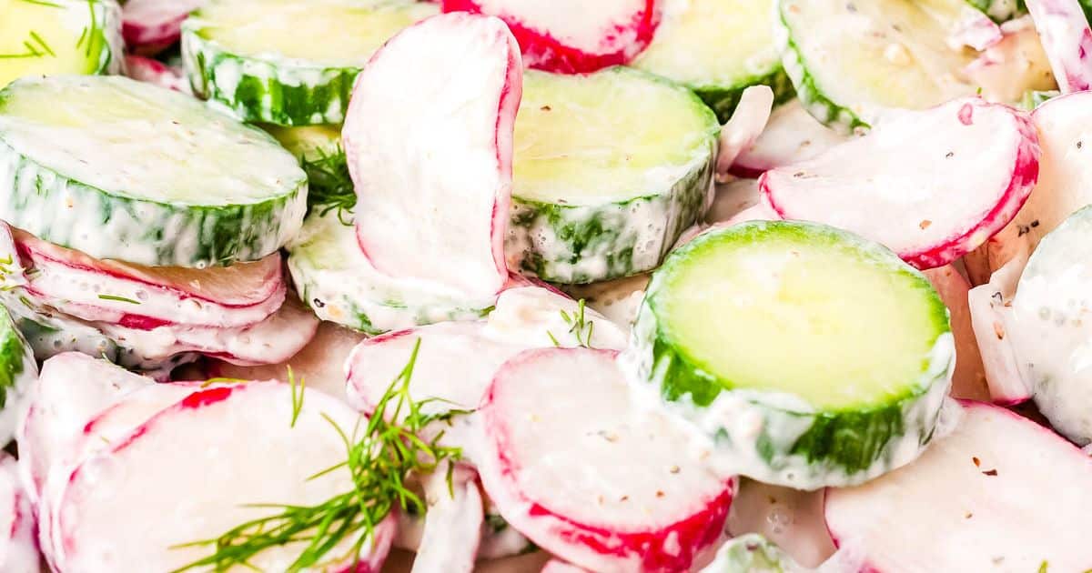 Cucumber and radish slices in creamy dressing, garnished with fresh dill sprigs.