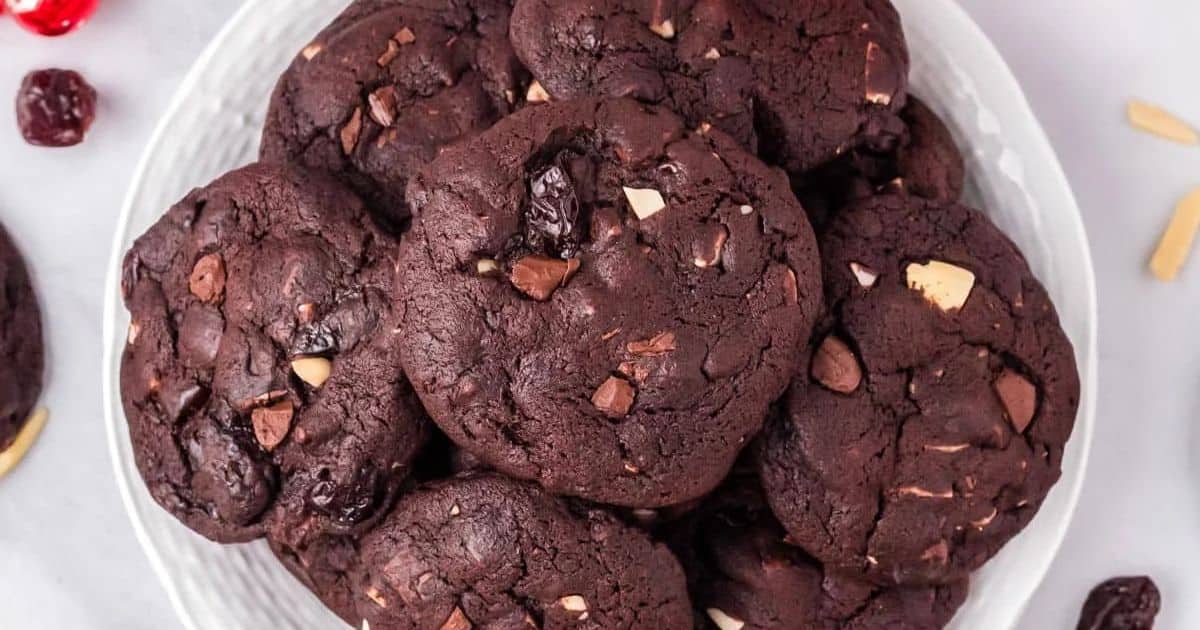 A plate of double chocolate cookies with chocolate chunks and nuts, viewed from above.