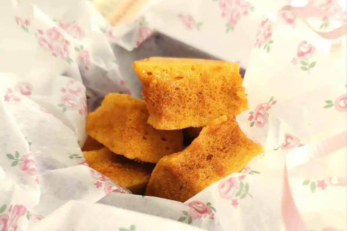 Four pieces of golden honeycomb toffee on floral-patterned parchment paper.