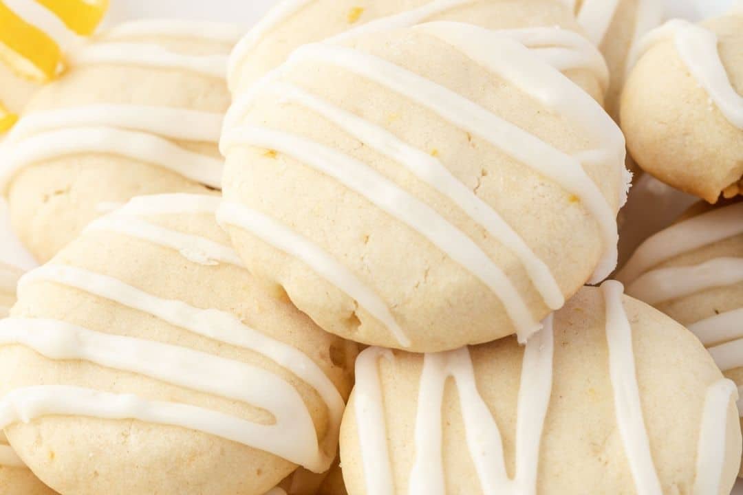 A pile of round, pale cookies drizzled with white icing on top.
