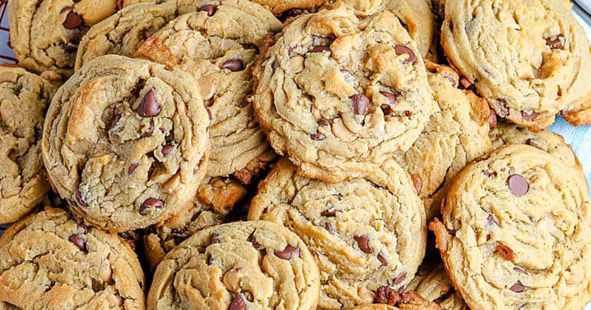 A pile of homemade chocolate chip cookies with golden brown edges and melted chocolate chips.