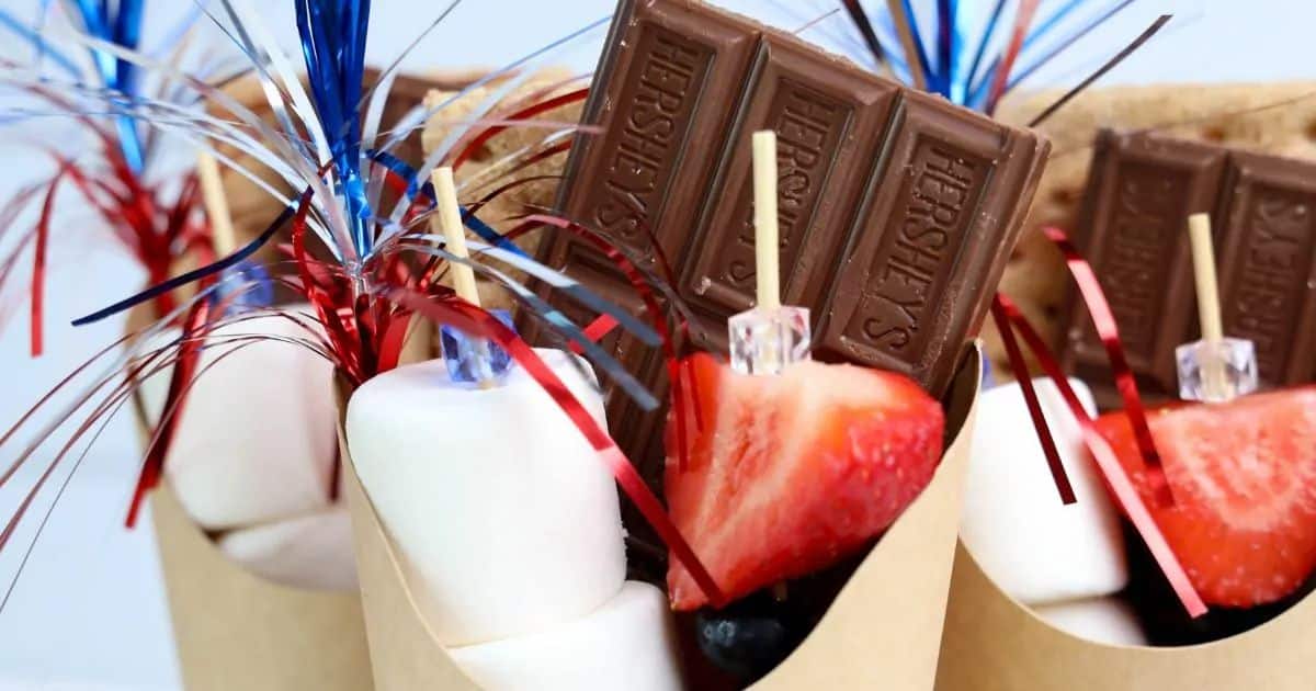 Paper cones with marshmallows, chocolate, strawberries, and festive red, white, and blue decorations.